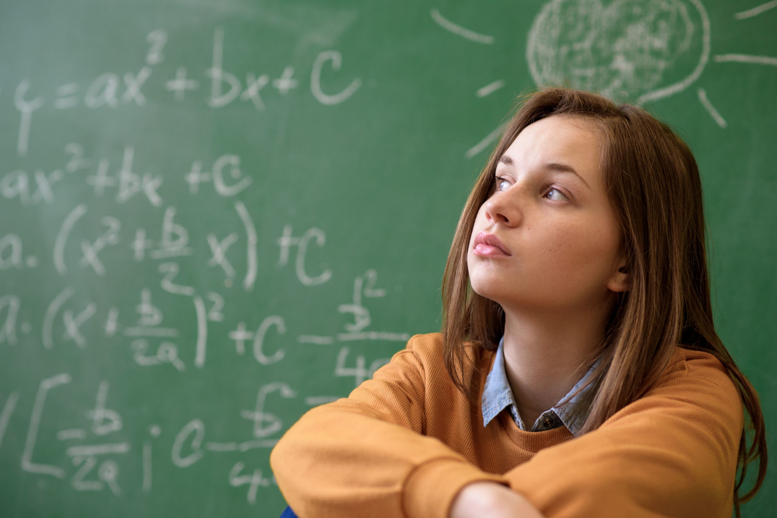 girl student contemplating in front of chalkboard