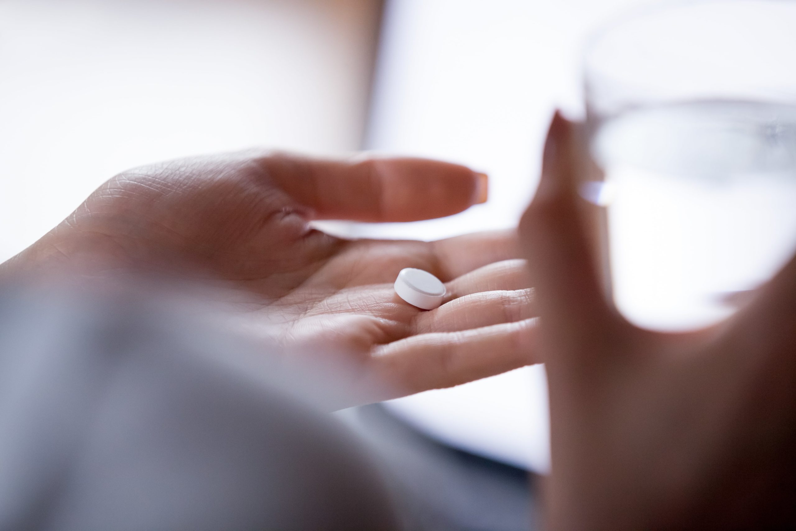 open hand holding medication in a white tablet form