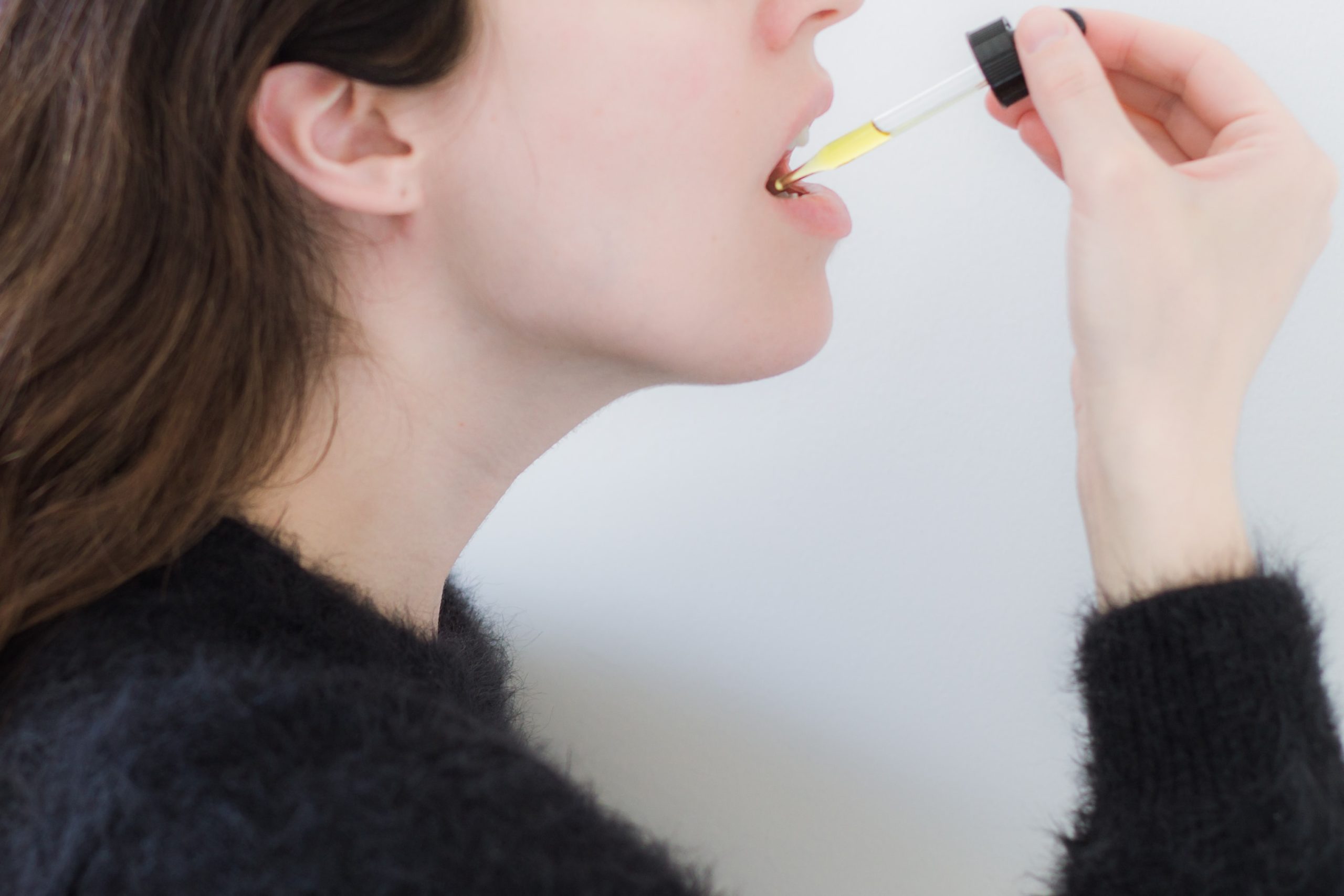 woman administering cbd oil tincture below tongue